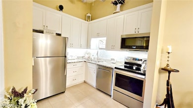 Kitchen with white cabinetry, a sink, light tile p