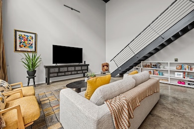 Living room featuring concrete floors, a towering ceiling, and stairs