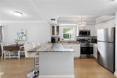 Kitchen with a kitchen bar, crown molding, stainless steel appliances, white cabinets, and a peninsula