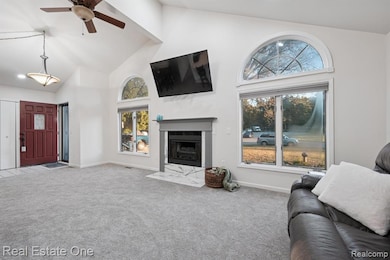 Living room with high vaulted ceiling, carpet, ceiling fan, a premium fireplace, and beam ceiling