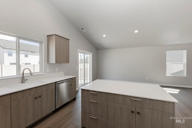 Kitchen featuring healthy amount of natural light, lofted ceiling, dark wood-style floors, modern cabinets, and dishwasher