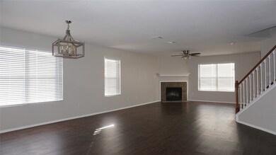 Unfurnished living room with dark wood-style floors, stairs, a fireplace, and ceiling fan