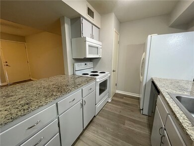 Kitchen featuring white cabinetry, light stone cou