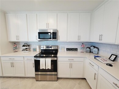 Kitchen with tasteful backsplash, white cabinetry, appliances with stainless steel finishes, and light tile patterned floors