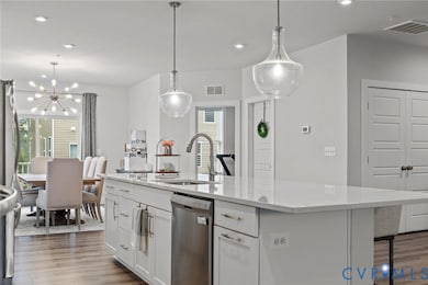 Kitchen with a center island with sink, recessed lighting, hanging light fixtures, dishwasher, and white cabinetry