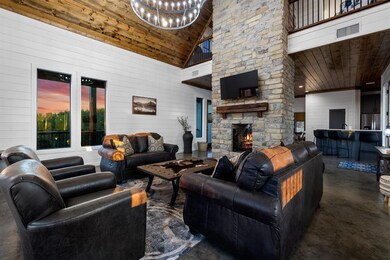 Living area featuring wood walls, concrete flooring, an outdoor stone fireplace, high vaulted ceiling, and wooden ceiling
