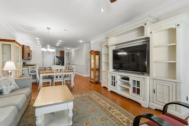 Living room with crown molding, wood finished floors, a chandelier, recessed lighting, and a ceiling fan