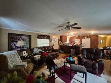 Living room with lofted ceiling, a ceiling fan, light wood finished floors, and ornamental molding