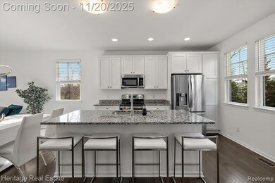 Kitchen featuring a breakfast bar area, light stone counters, white cabinets, a center island with sink, and dark wood-type flooring