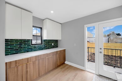 Kitchen featuring modern cabinets, tasteful backsplash, light wood-style floors, white cabinetry, and brown cabinetry