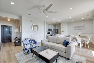 Living area with light wood finished floors, a decorative wall, a wainscoted wall, recessed lighting, and ceiling fan