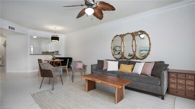 Living room with crown molding, a ceiling fan, til