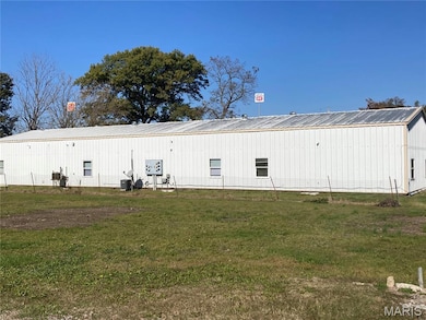 Back of house with a yard, a metal roof, and an outbuilding