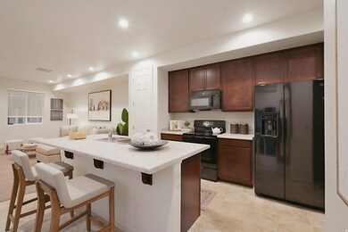 Kitchen with black appliances, light countertops, a breakfast bar, recessed lighting, and open floor plan