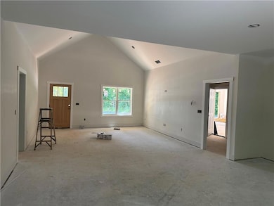 Unfurnished living room with high vaulted ceiling and baseboards
