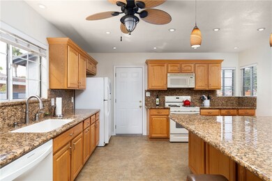 Remodeled kitchen with wood cabinets, granite counters and backsplash. Love the pendant lights and ceiling fan.