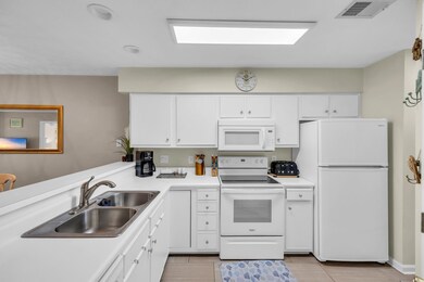 Kitchen with white appliances, white cabinetry, and light countertops