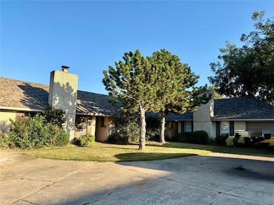 View of front of house with a chimney, brick siding, a front yard, and roof with shingles