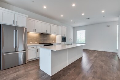 Kitchen with white cabinetry, backsplash, visible 