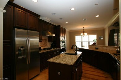 Kitchen with stainless steel appliances, double ovens, gas cooktop, granite, tile backsplash, recessed lighting, and island with 2nd sink.