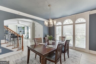 Dining space featuring arched walkways, a chandelier, light wood-style flooring, stairs, and crown molding