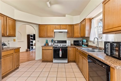 Kitchen featuring black appliances, a sink, under