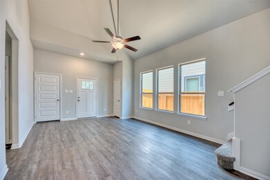 Taking another perspective of the family room, you'll notice a coat closet conveniently positioned near the entrance, offering a practical storage option. An overhead suspended fan enhances comfort by ensuring effective air circulation. This room features ample space to accommodate large furniture arrangements.