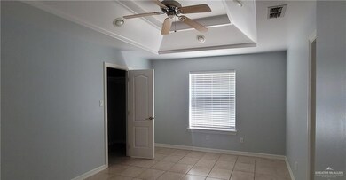 Spare room featuring a tray ceiling, ceiling fan, light tile patterned flooring, and baseboards