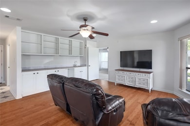 Living room featuring a ceiling fan, light wood-t