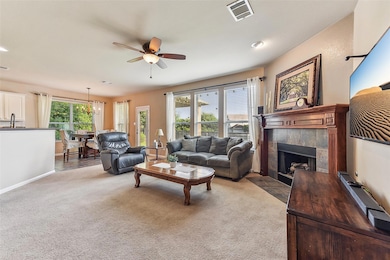 Living area featuring a fireplace, ceiling fan, c