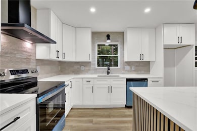 Kitchen featuring electric stove, wall chimney exhaust hood, dishwashing machine, a sink, and tasteful backsplash