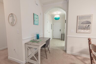 Hallway featuring crown molding, carpet flooring, arched walkways, a chandelier, and baseboards