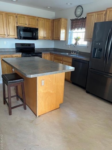 Kitchen with a kitchen island, refrigerator, light floors, stove, and a breakfast bar