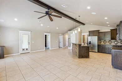 Kitchen with backsplash, appliances with stainless steel finishes, pendant lighting, open floor plan, and dark brown cabinetry