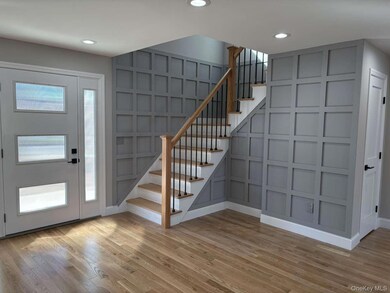 Entryway featuring a decorative wall, stairs, light wood-type flooring, and recessed lighting