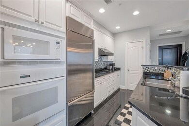 Kitchen with built in appliances, white cabinetry, tasteful backsplash, recessed lighting, and dark stone counters