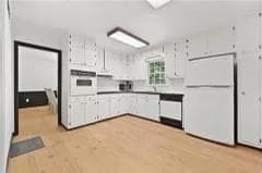 Kitchen with refrigerator, oven, white cabinets, and light wood-style floors