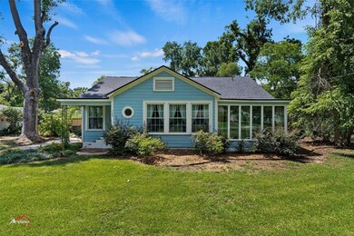 Back of property with a lawn and a sunroom