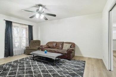 Living room with light wood-type flooring and a ceiling fan