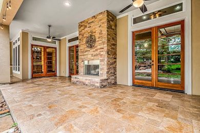 French doors throughout the home allow you to step onto a covered patio that embodies the essence of outdoor living!  This grand stone fireplace stands as a focal point.  Travertine pavers add to the warmth and style of the outdoor space.