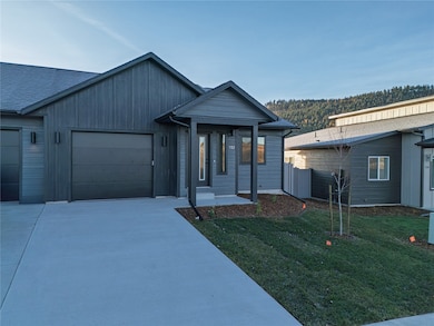 View of front of property featuring concrete driveway, an attached garage, and a front yard