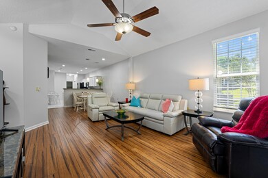 Living area featuring ceiling fan, wood-type flooring, lofted ceiling, and baseboards