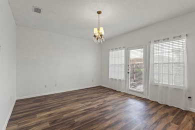 Unfurnished room with a chandelier, dark wood-style flooring, and a textured ceiling