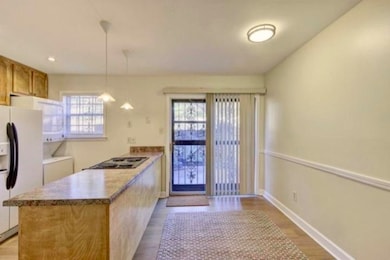 Kitchen with a peninsula, white fridge with ice dispenser, light wood-style floors, pendant lighting, and washer / clothes dryer