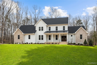 Modern farmhouse style home with metal roof, a standing seam roof, a front yard, board and batten siding, and brick siding