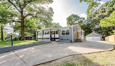 View of front of home with a garage, covered porch, an outdoor structure, and a front yard