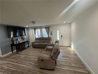 Living area featuring baseboards, recessed lightin
