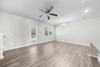 Empty room with a chandelier, stairs, light wood finished floors, ceiling fan, and baseboards