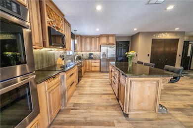 Kitchen featuring black appliances, light wood-sty