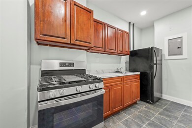 Kitchen featuring stainless steel range with gas cooktop, freestanding refrigerator, dark tile patterned flooring, brown cabinetry, and recessed lighting